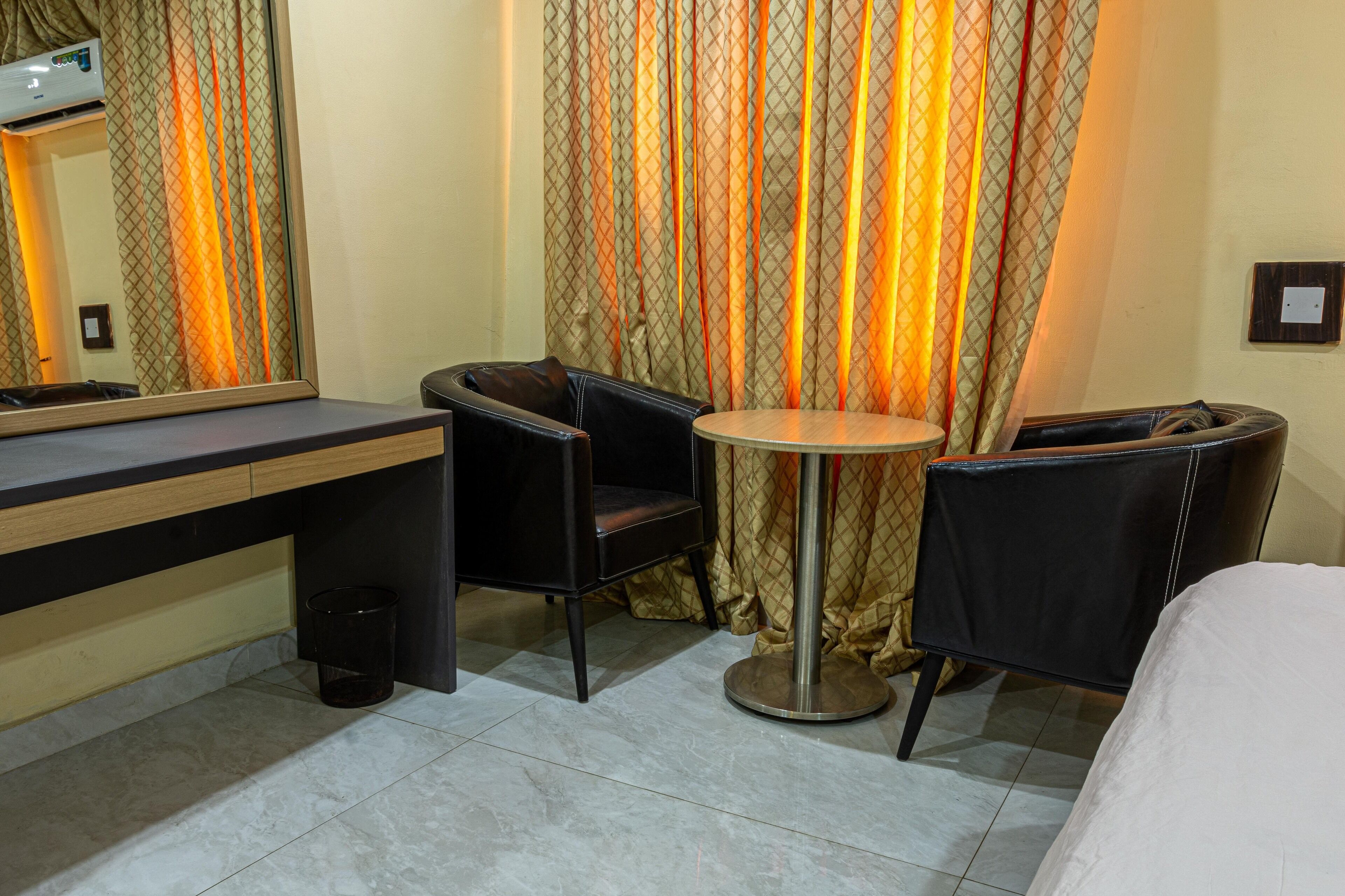 A hotel room with a bed, a desk, a chair, and a small round table.