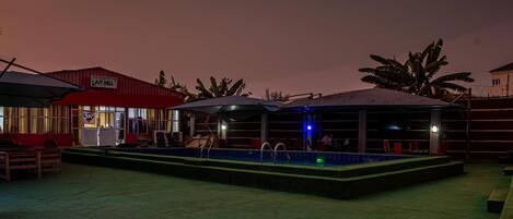 An outdoor pool area with a covered seating area and a building labeled "JOY HALL".