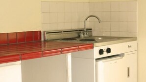 A compact kitchen with a red countertop, a sink, and a white stove. - Orchard Garden Hotel & Suites (Nassau)