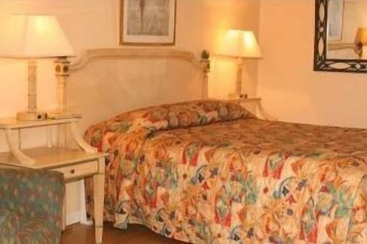 Une chambre d’hôtel avec un lit, deux tables de chevet et des lampes.
