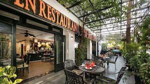 An outdoor restaurant with a covered patio, tables, chairs, and potted plants. - Hoi An Golden Holiday Elite (Da Nang)