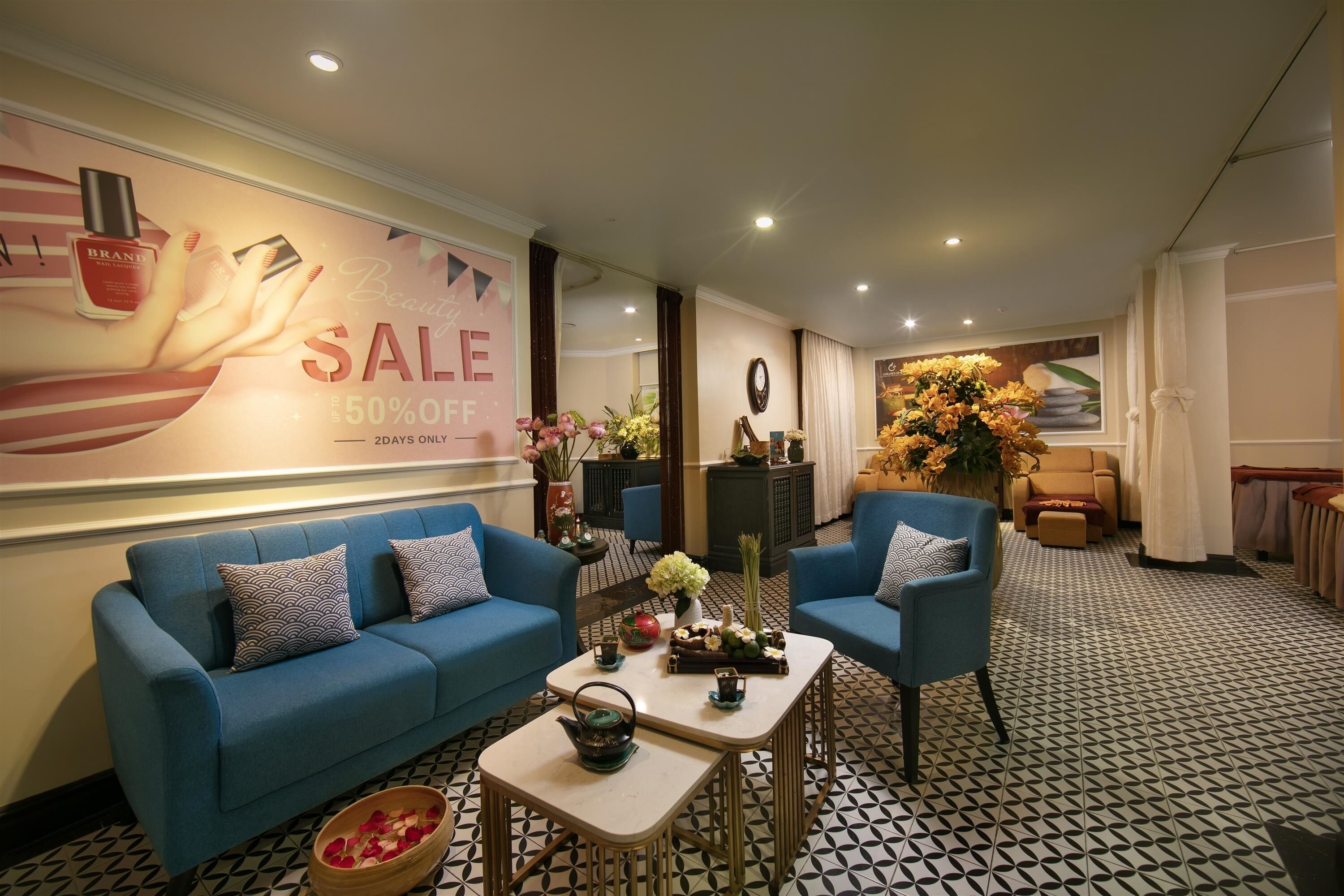 A modern lounge area with a blue sofa, a small table with a teapot, and a patterned floor.