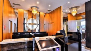 A modern reception area with a digital check-in station, wooden paneling, and a chandelier. - APA Hotel Nihonbashi Hamacho Ekiminami (Tokyo)