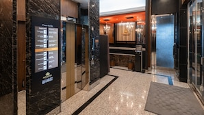 A hotel lobby with a marble floor, a chandelier, a front desk, and a vending machine. - APA Hotel Hatchobori Ekiminami (Tokyo)