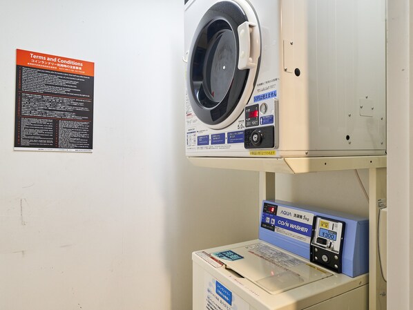 A laundry area with a washing machine and dryer, a sign with terms and conditions, and a price tag on the dryer. - APA Hotel Toyama Ekimae Minami (Toyama)