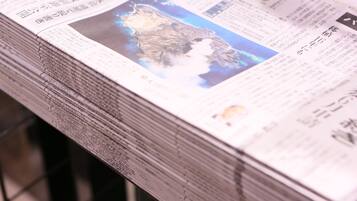 A stack of newspapers with a map and text on the front page.