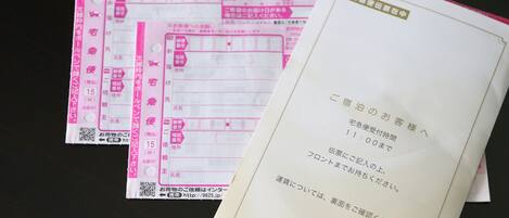A stack of pink hotel check-in forms and a white envelope with hotel branding.