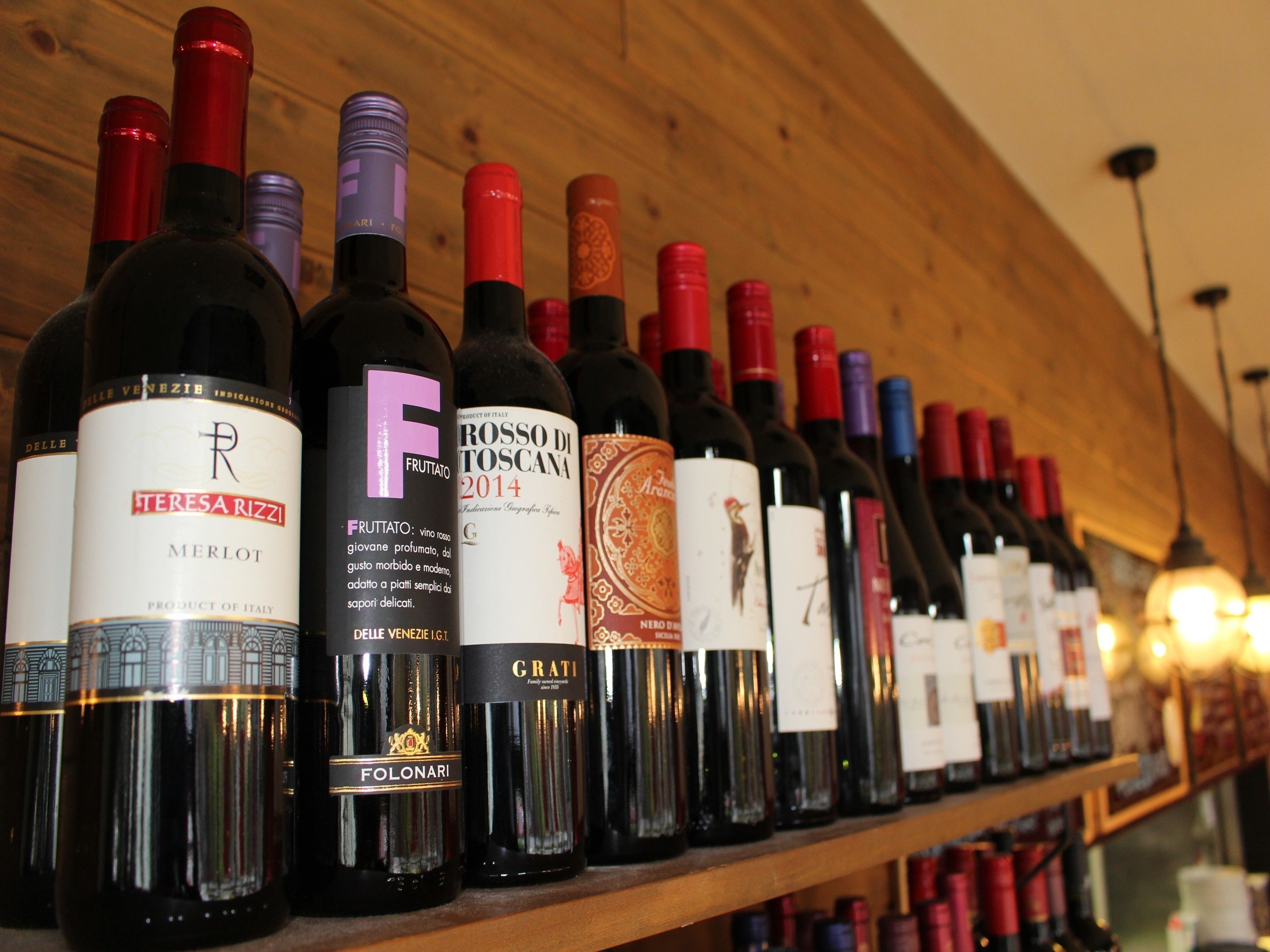 A row of wine bottles on a shelf in a wooden interior.