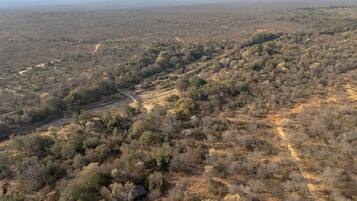 An aerial view of a dry, hilly landscape with sparse vegetation and a few scattered buildings.
