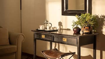 Een kamer met een donker houten bureau, een kleine stoel, een vloerlamp, een spiegel en een potplant.