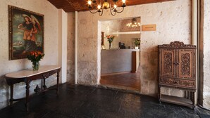 Zona de recepción con techo de madera, mostrador de recepción, espejo y un mueble decorativo.