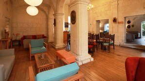 Un vestíbulo amplio con suelo de madera, una zona de estar con sofás y sillones, y un gran arco de entrada.