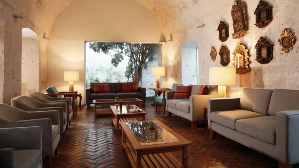 Una sala de estar acogedora con suelo de ladrillo, un sofá, sillones y una mesita de centro.