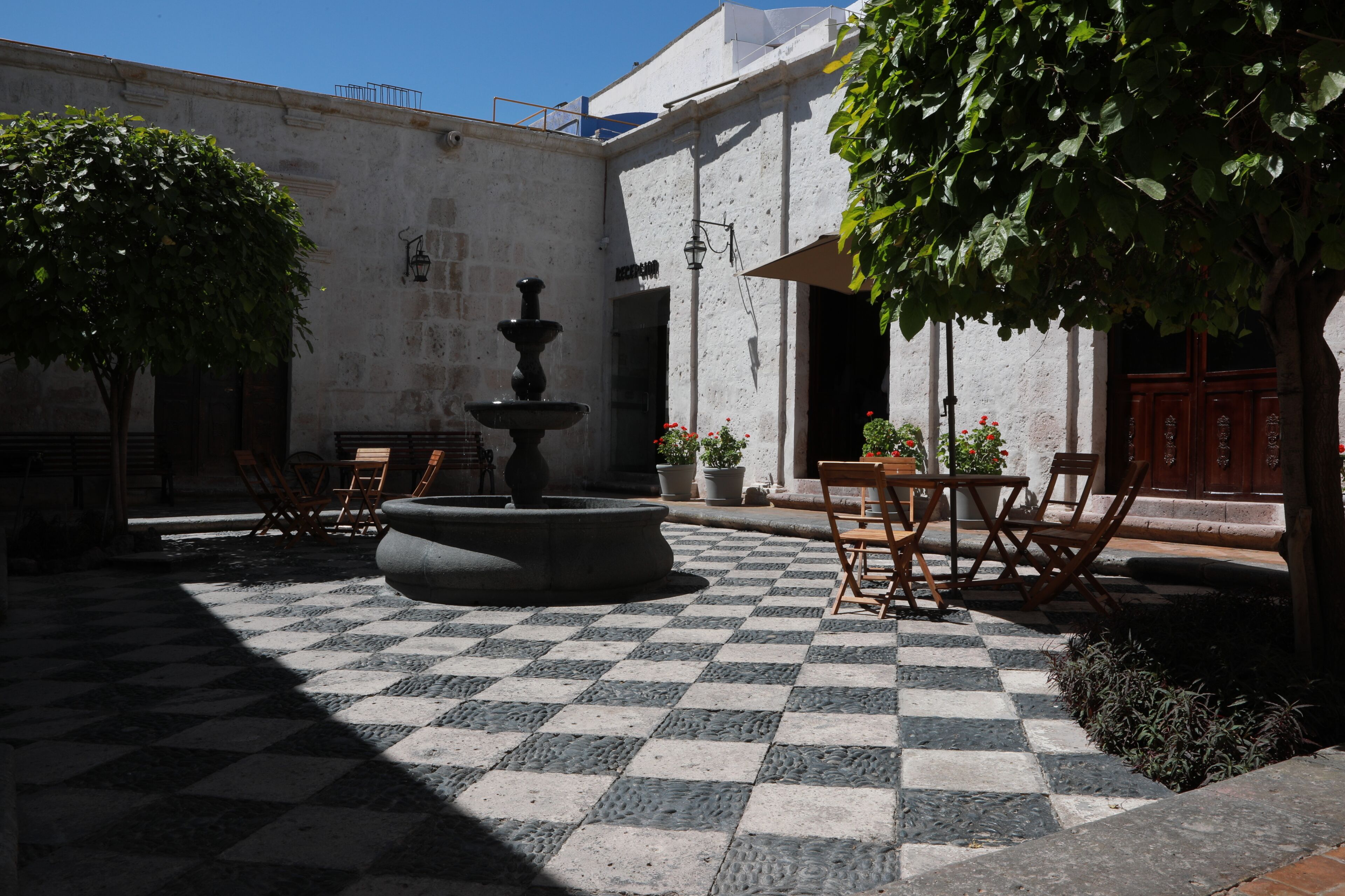 Un patio con fuente, suelo a cuadros y mobiliario exterior.