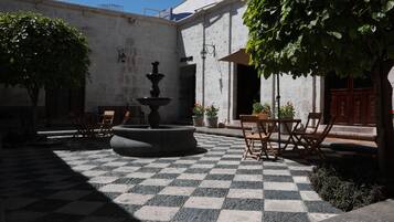 Un patio con fuente, suelo a cuadros y mobiliario exterior.