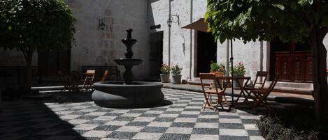 Un patio con fuente, suelo a cuadros y mobiliario exterior.