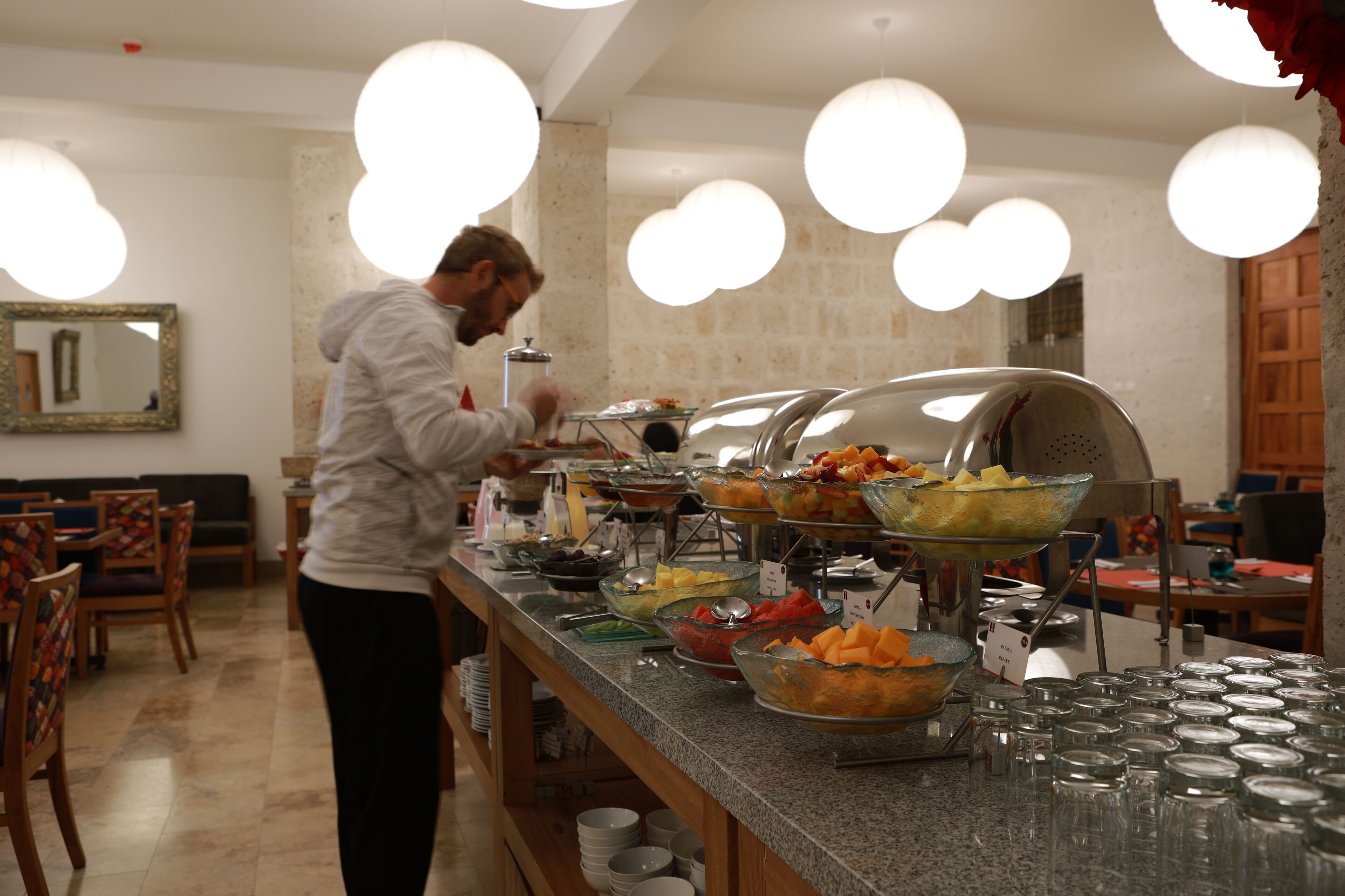 A buffet setup with various food items and a person serving.