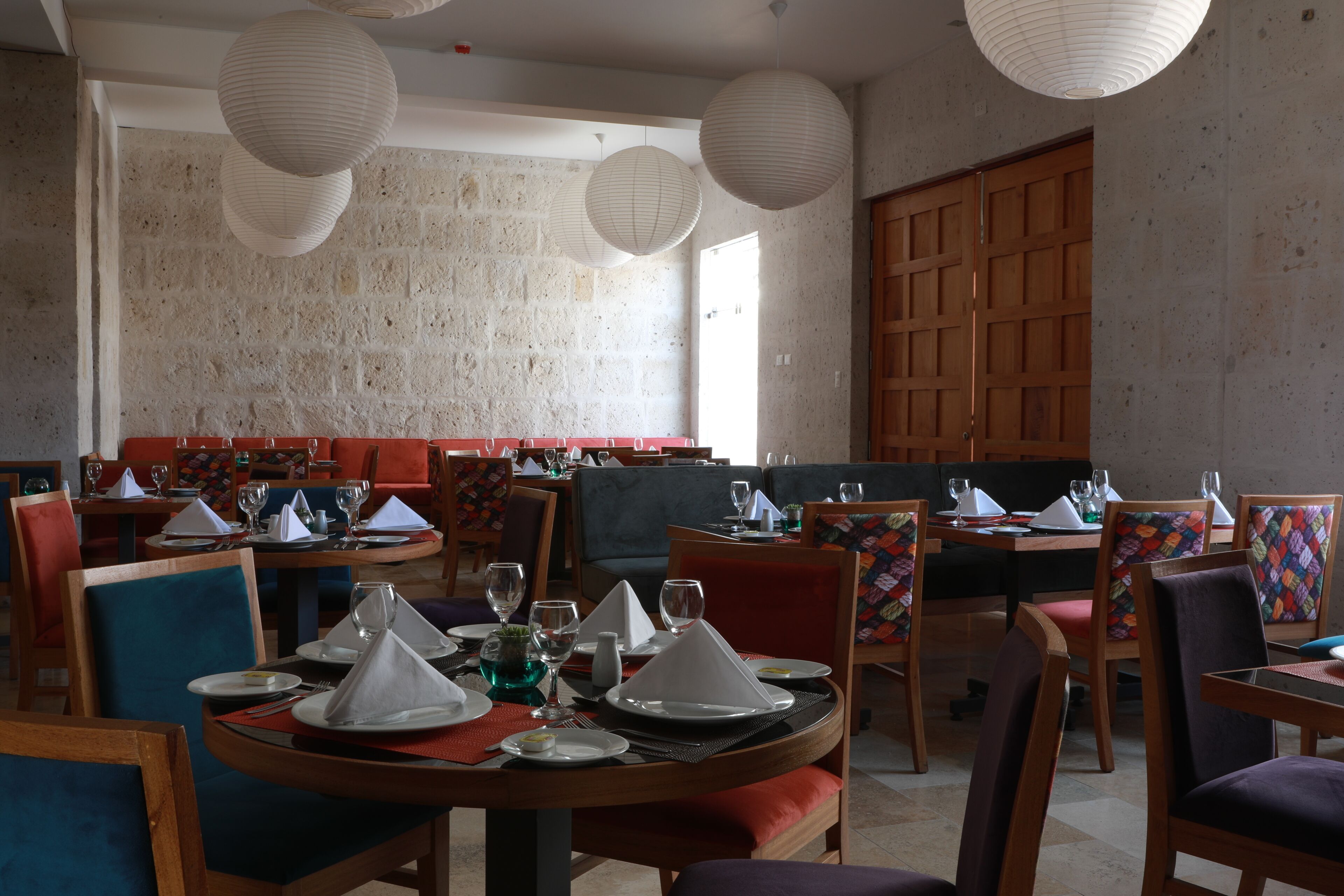 Un restaurante con mesas redondas, sillas y faroles de papel colgantes.