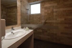 Un baño con lavabo, espejo y zona de ducha.