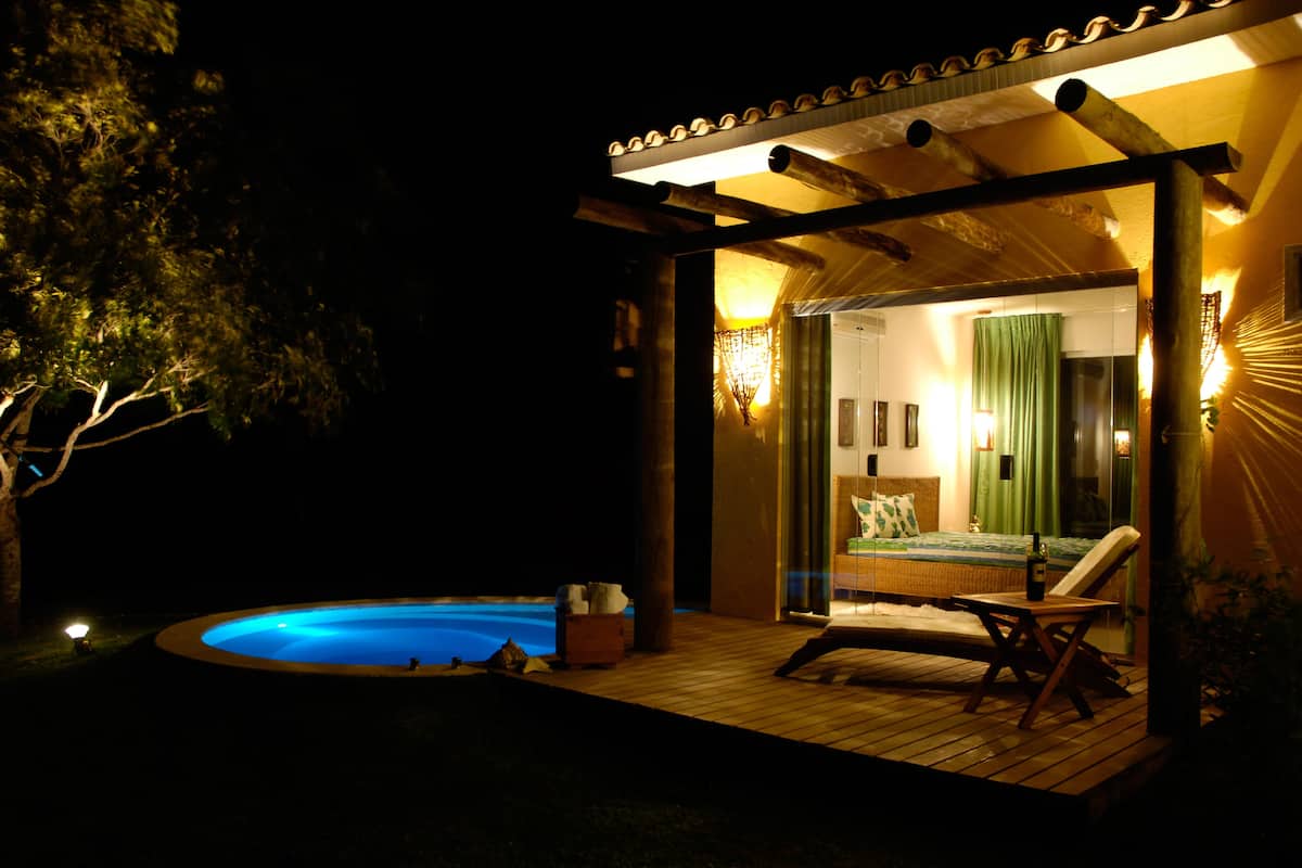 A private villa with a swimming pool, a bedroom with a bed and a green curtain, and a wooden deck.