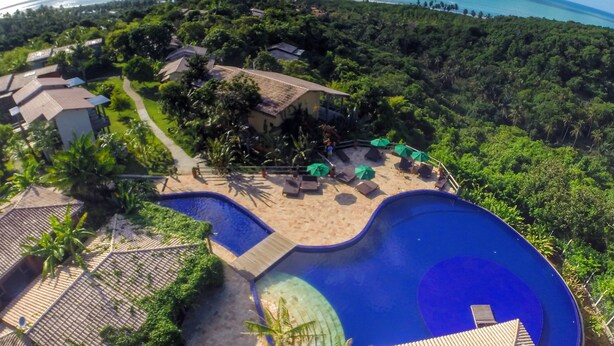 Un resort con una amplia piscina, zona de playa y vistas al océano.