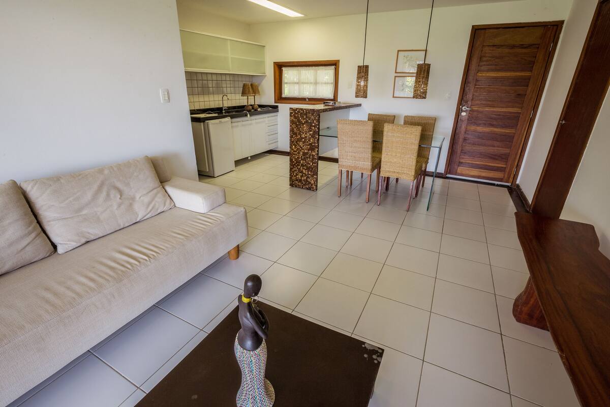 A living room with a sofa, a coffee table, and a dining area with chairs and a table.
