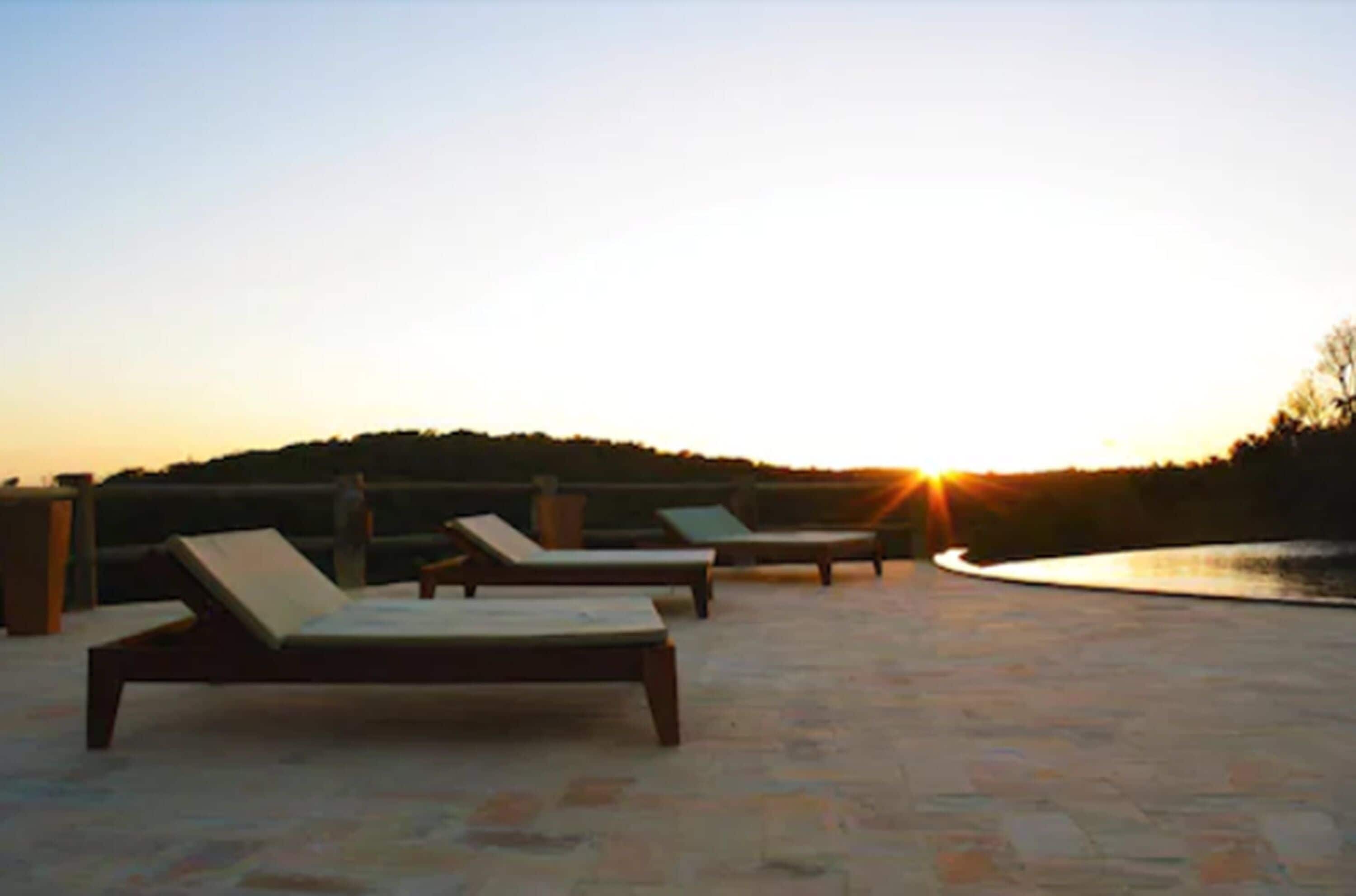 Terraza en la azotea con sillones de descanso y vista al atardecer sobre un cuerpo de agua.