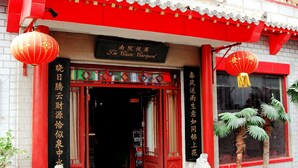 A traditional Chinese building with red and white exterior, a sign reading "The Classic Courtyard," and a large red lantern. - The Classic Courtyard (Beijing)