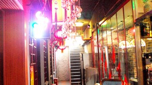 A narrow corridor with a staircase leading to an upper level, illuminated by hanging lanterns and a neon sign. - The Classic Courtyard (Beijing)