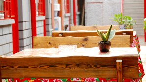 A wooden table with a potted plant and a glass. - The Classic Courtyard (Beijing)