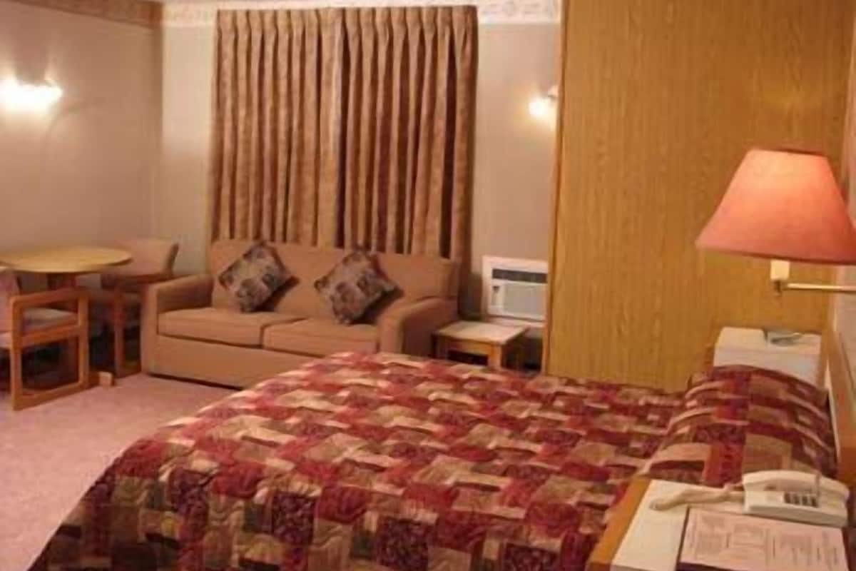 Una habitación de hotel con cama, sofá, mesita, lámpara y microondas.