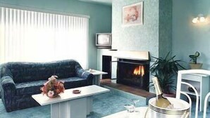 Una sala de estar con sofá, mesa de centro, chimenea y televisor.