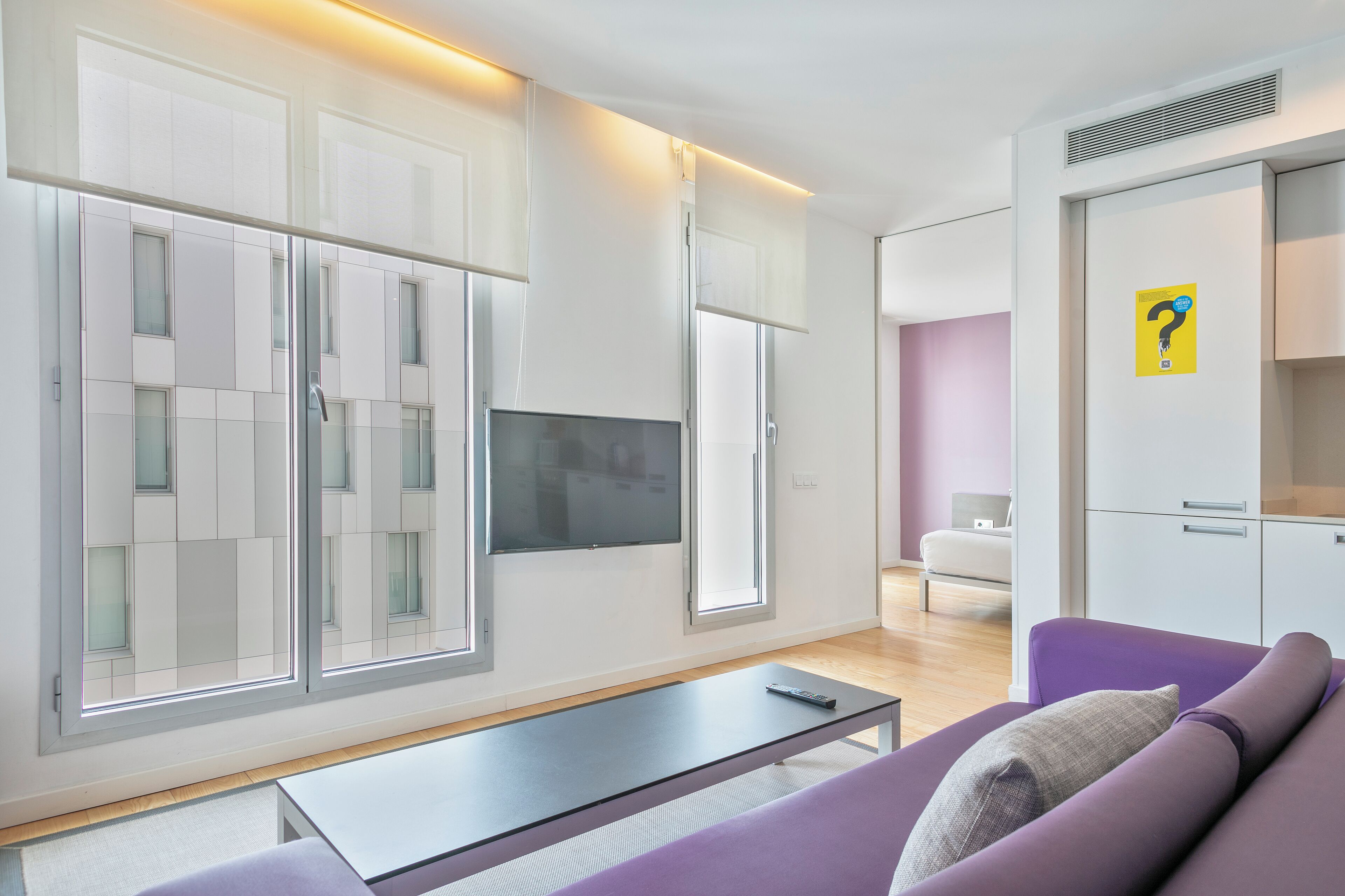 A modern living room with a sofa, a coffee table, and a TV mounted on the wall.