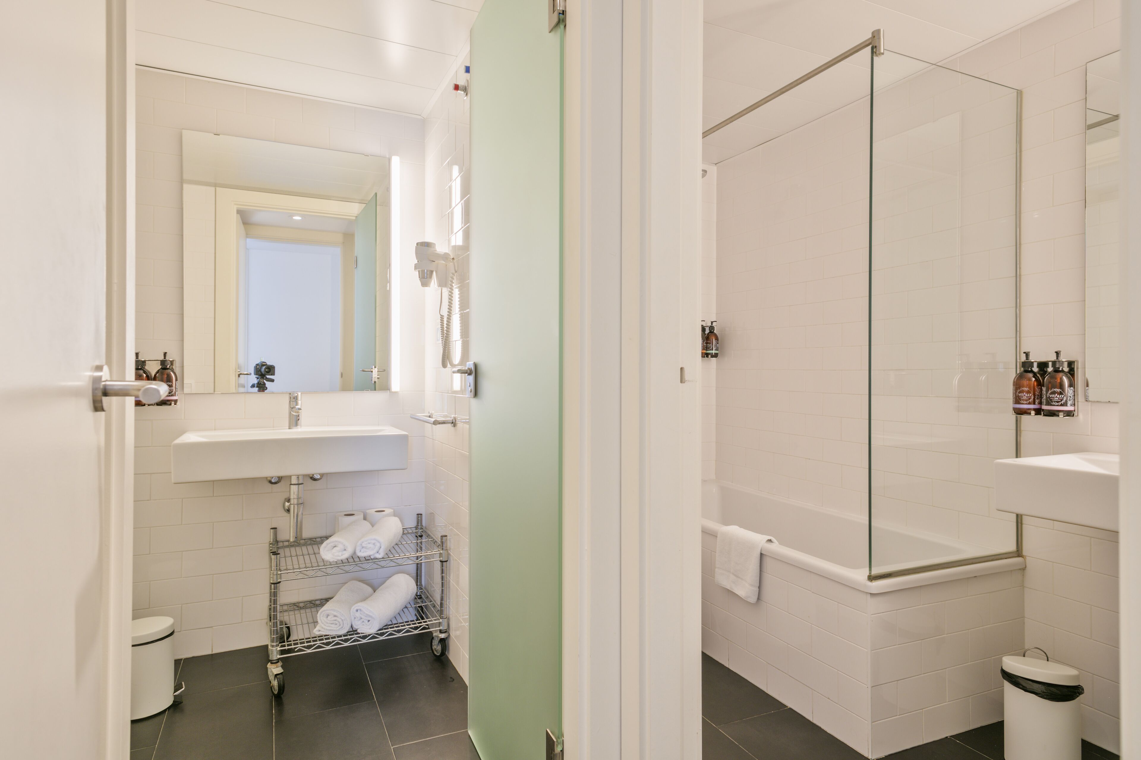 A bathroom with a shower, a sink, a toilet, and a towel rack.