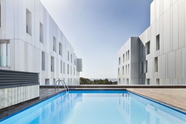 Un área de piscina moderna con una vista despejada del cielo y árboles lejanos.