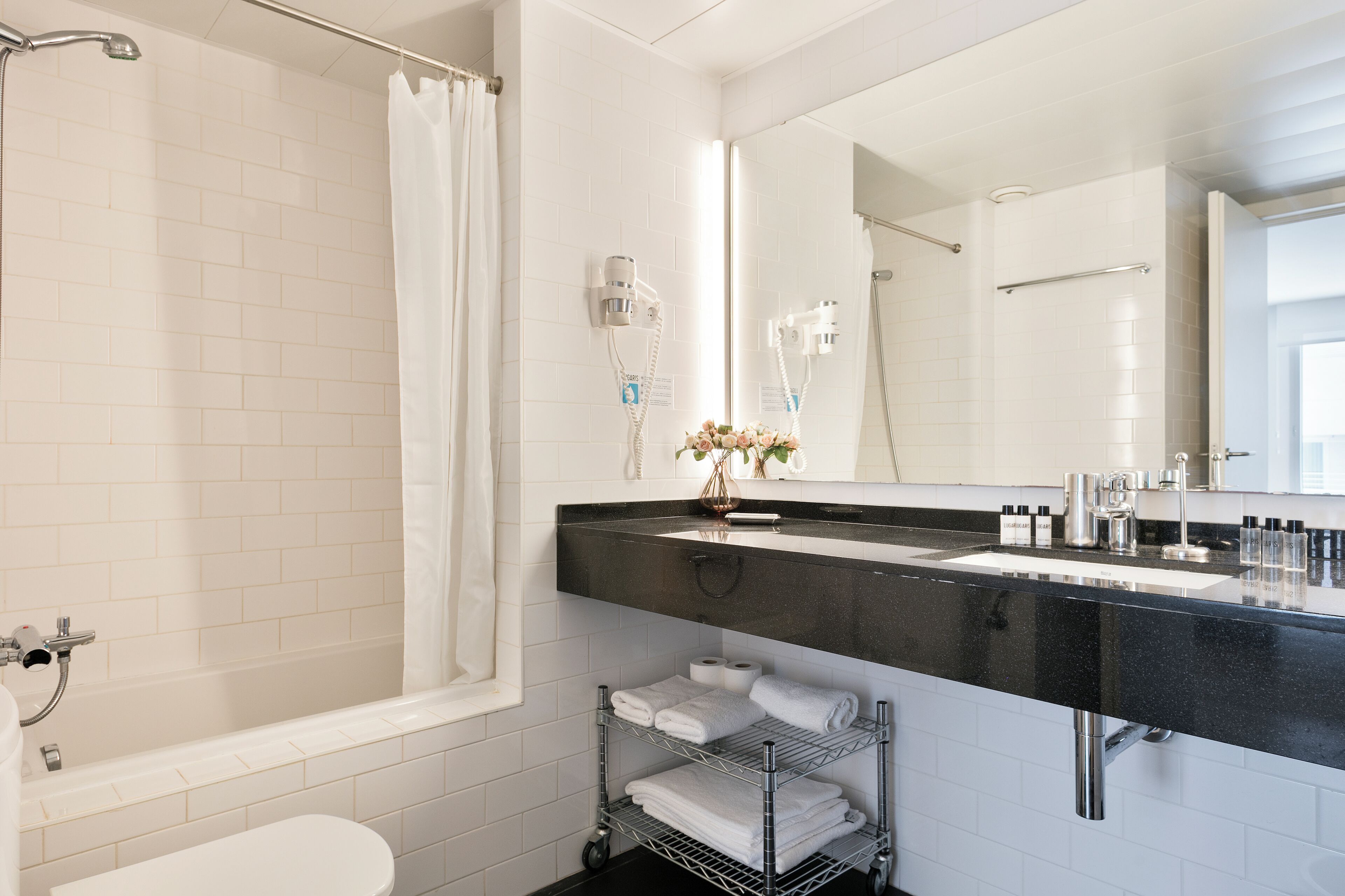 A modern bathroom with a bathtub, shower, and a vanity with a black countertop.