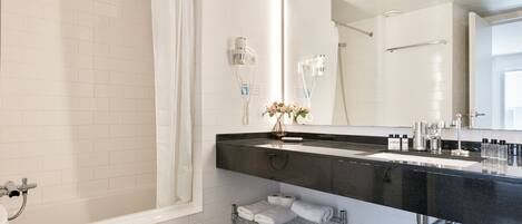 Een moderne badkamer met een badkuip, douche en een wastafelmeubel met een zwart aanrecht.
