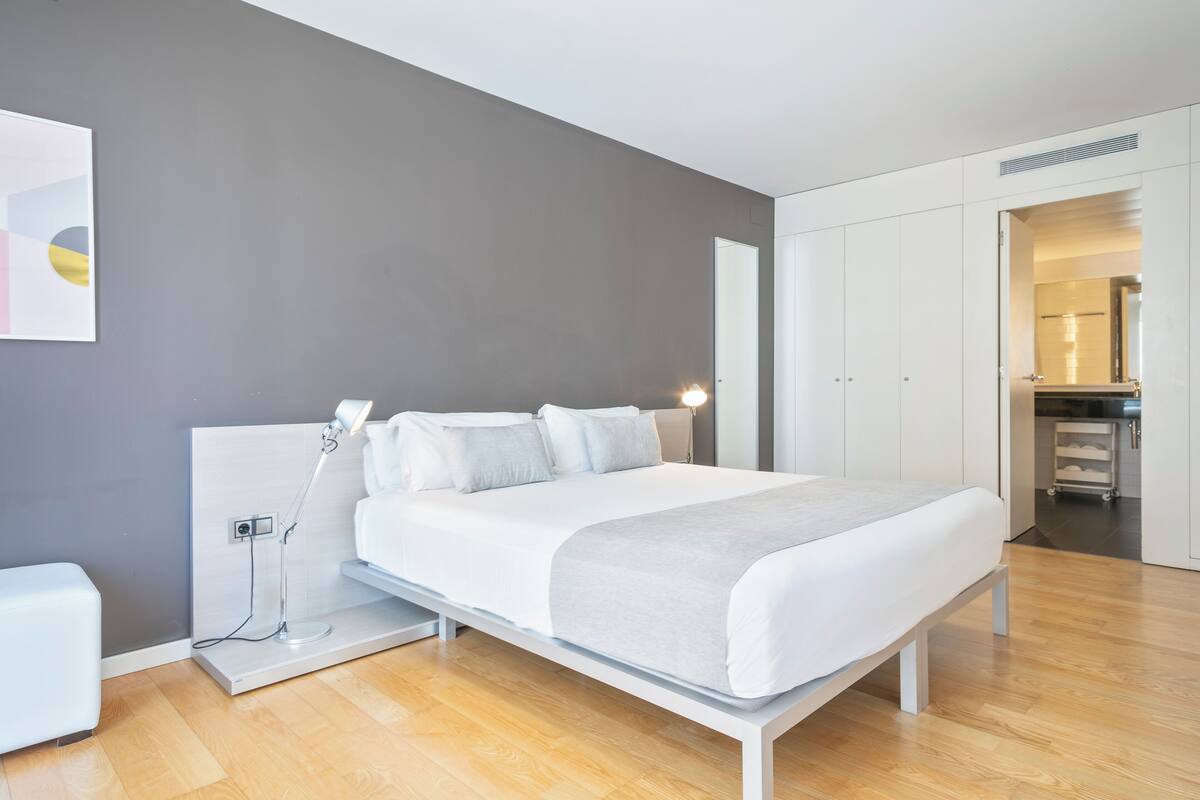 A modern bedroom with a bed, bedside table, and a nightstand.