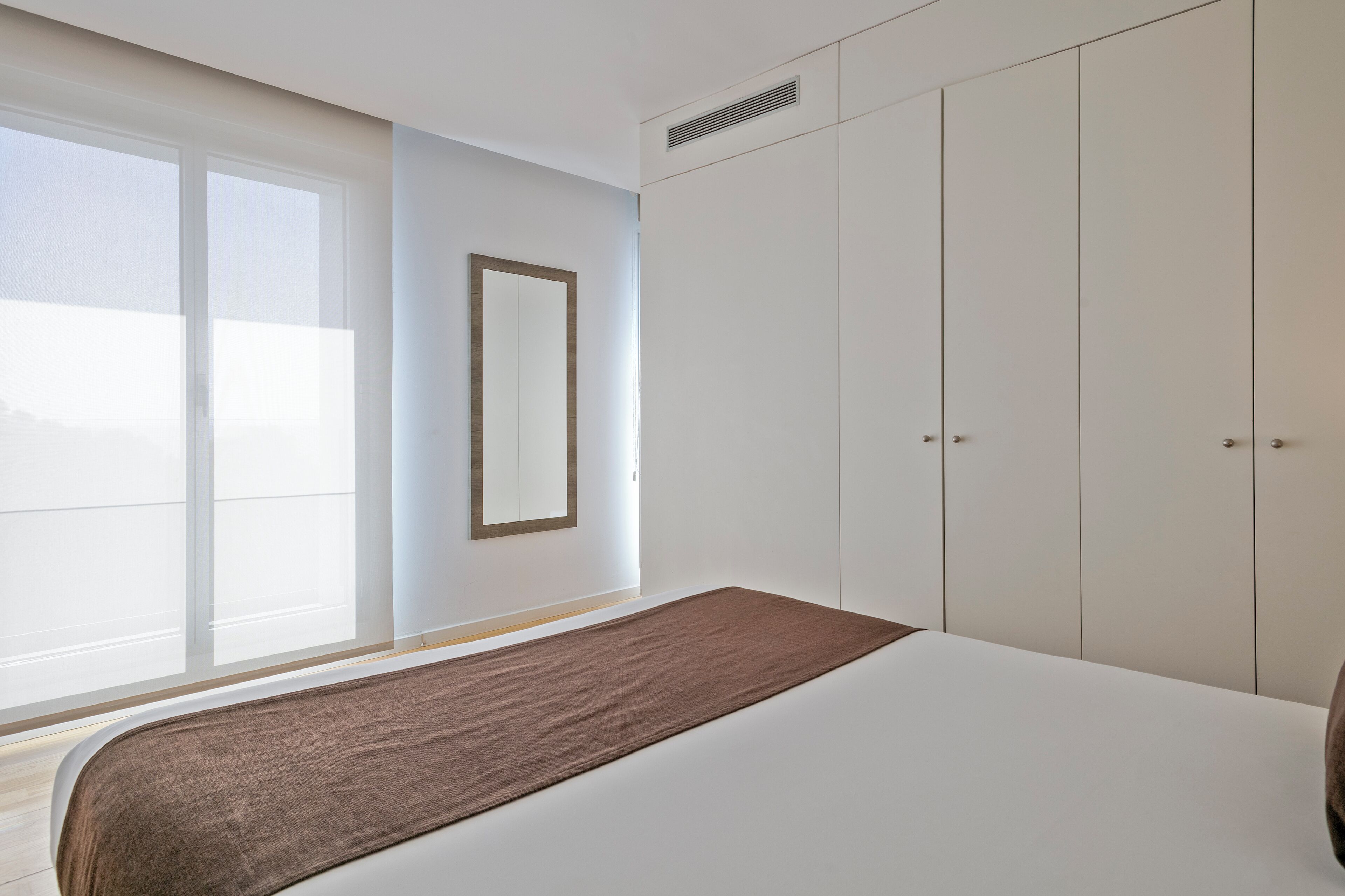 Ein Schlafzimmer mit einem großen Bett, einem Kleiderschrank und einem Fenster mit Jalousien.