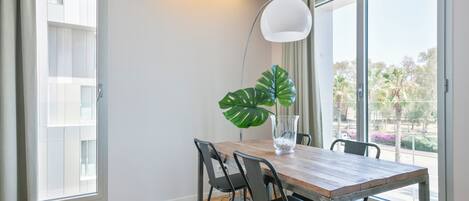 Un comedor con una mesa de madera, cuatro sillas, una planta en maceta y una lámpara de pie.