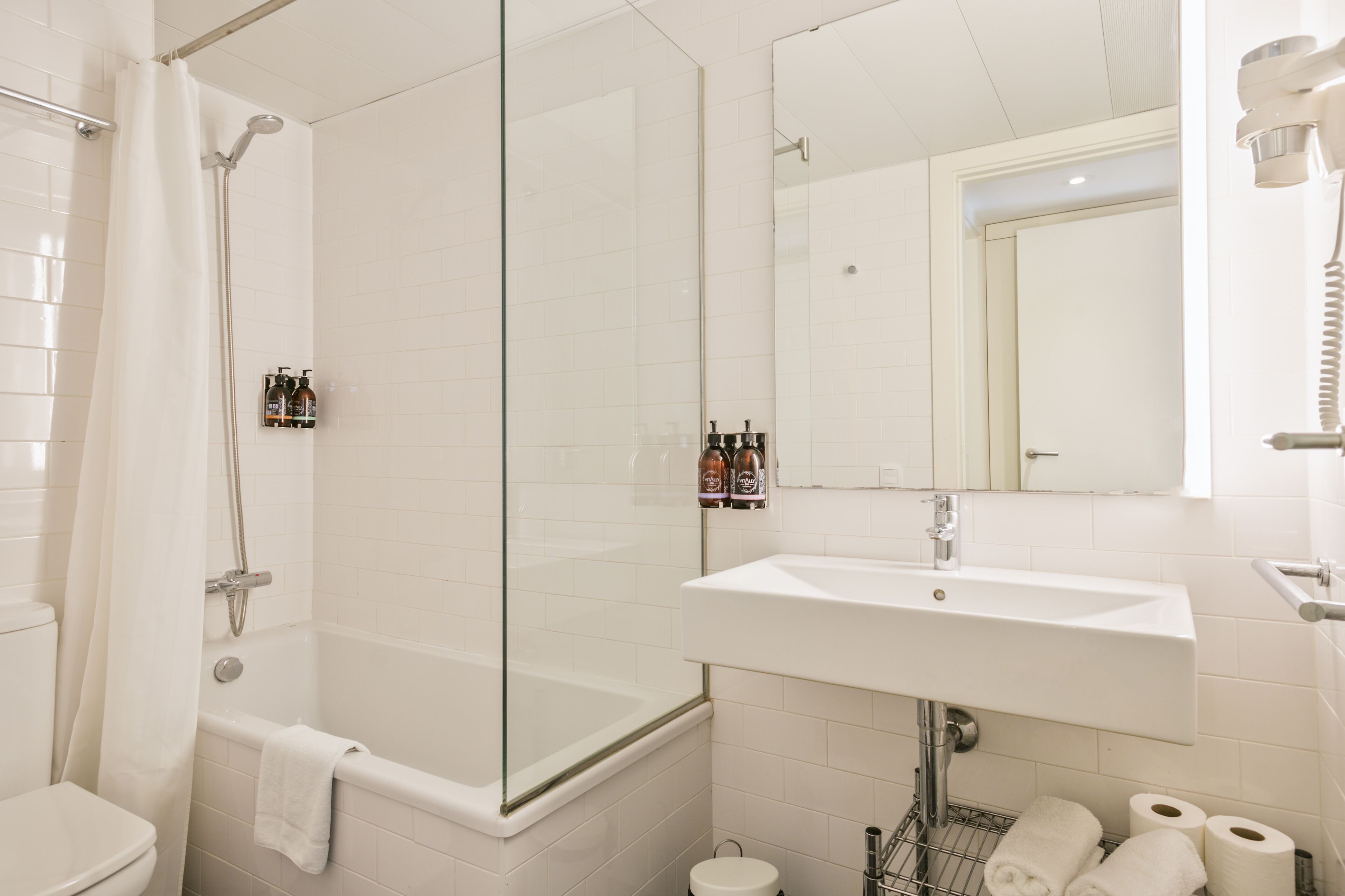 A modern bathroom with a glass-enclosed shower, a white sink, and a toilet.
