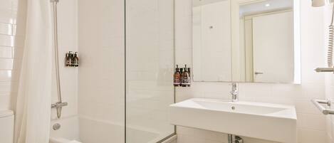A modern bathroom with a glass-enclosed shower, a white sink, and a toilet.