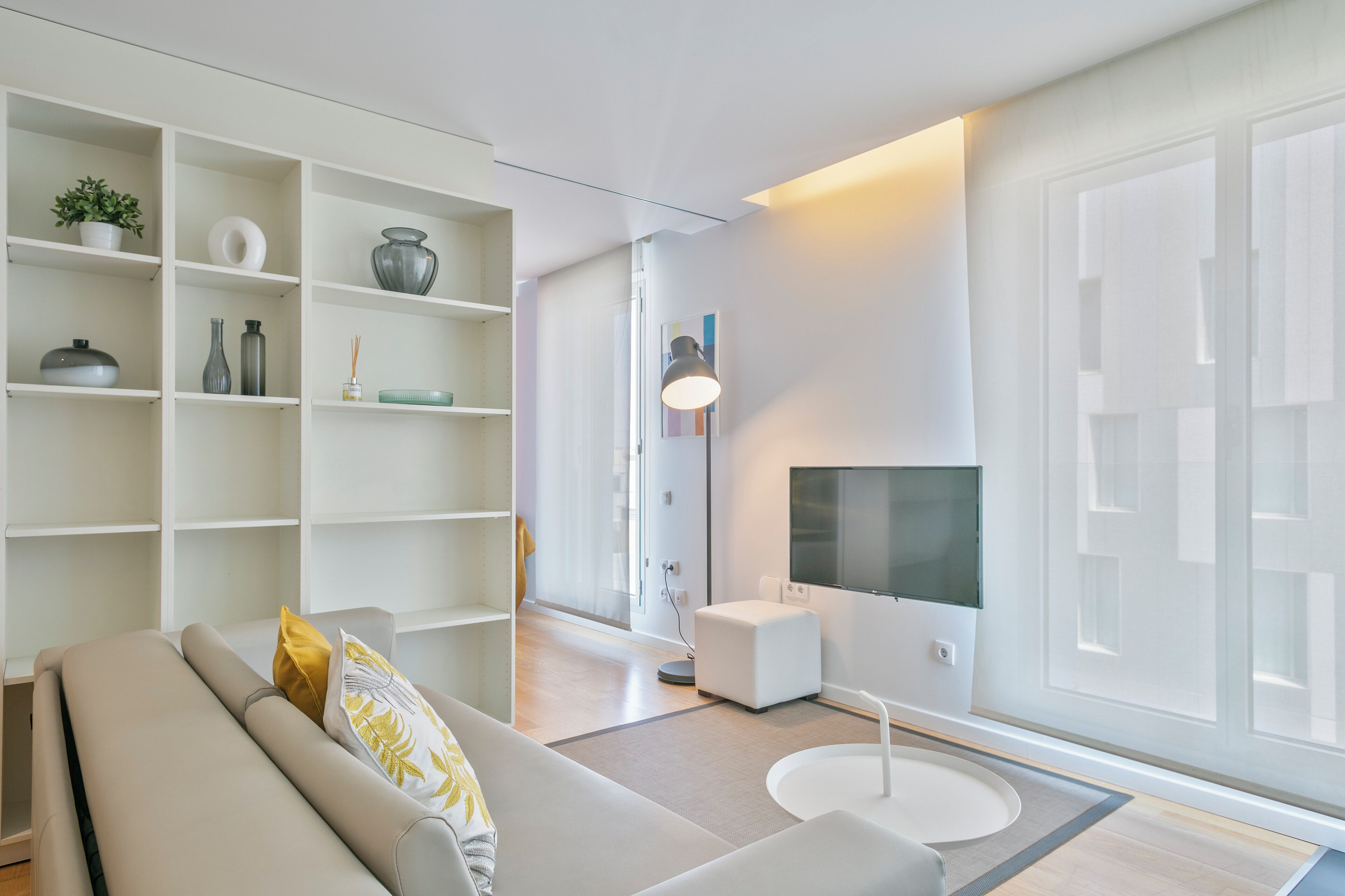 Ein modernes Wohnzimmer mit einer Couch, einem Fernseher, einem Bücherregal und einem kleinen Beistelltisch.
