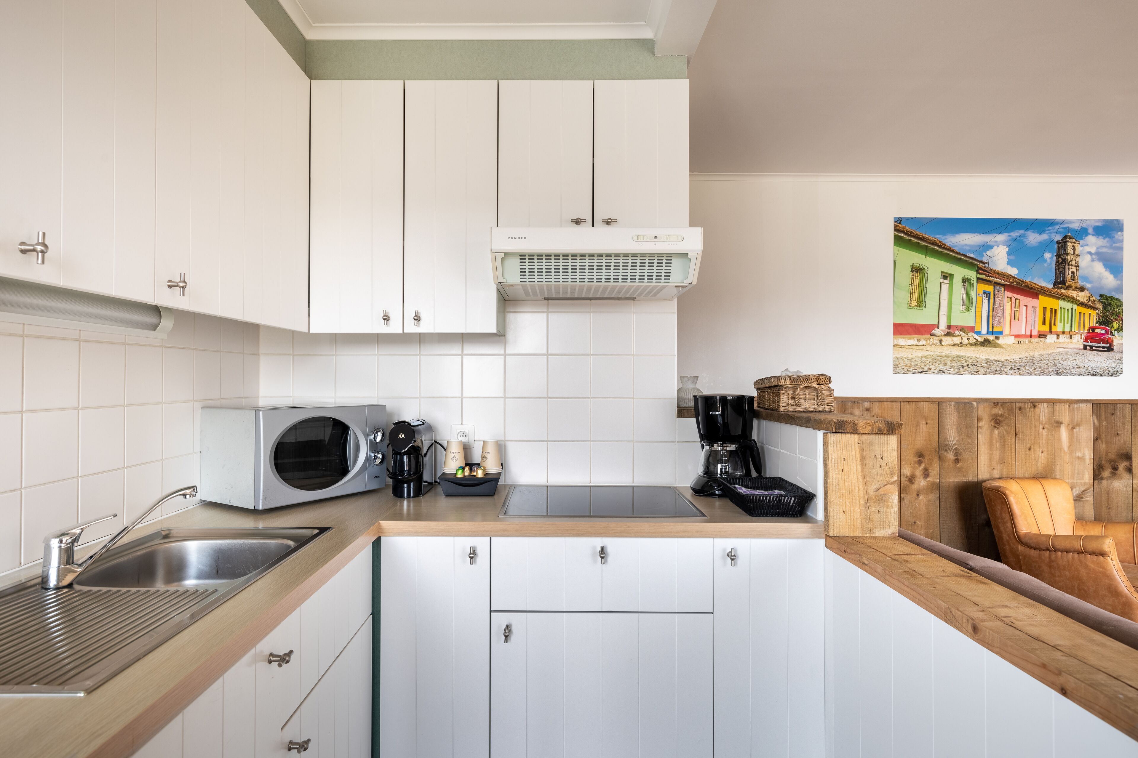 Een moderne keuken met witte kasten, een ingebouwde magnetron en een koffieapparaat.