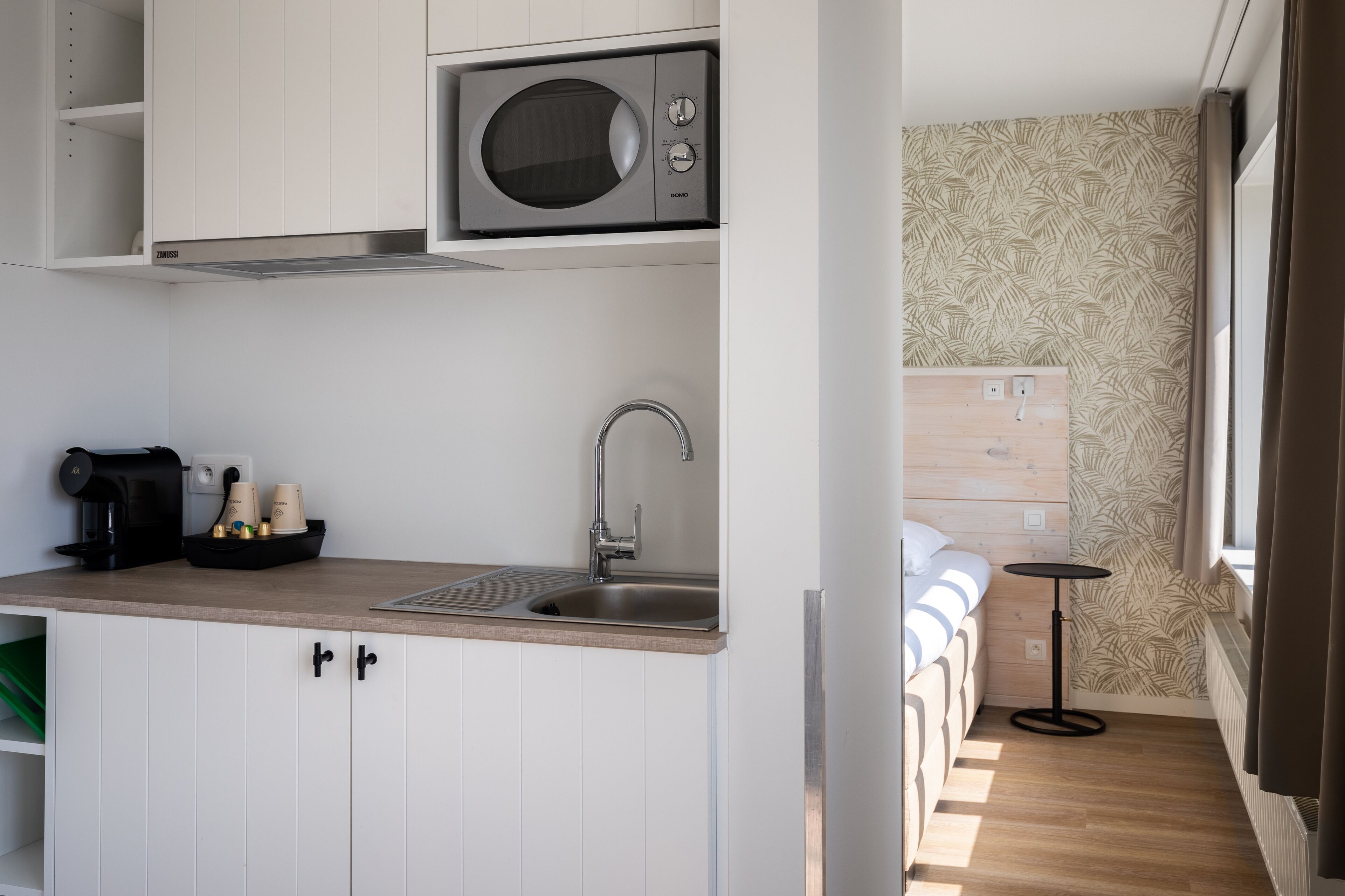 A compact kitchenette with a microwave, sink, and coffee maker.