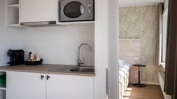 A compact kitchenette with a microwave, sink, and coffee maker.