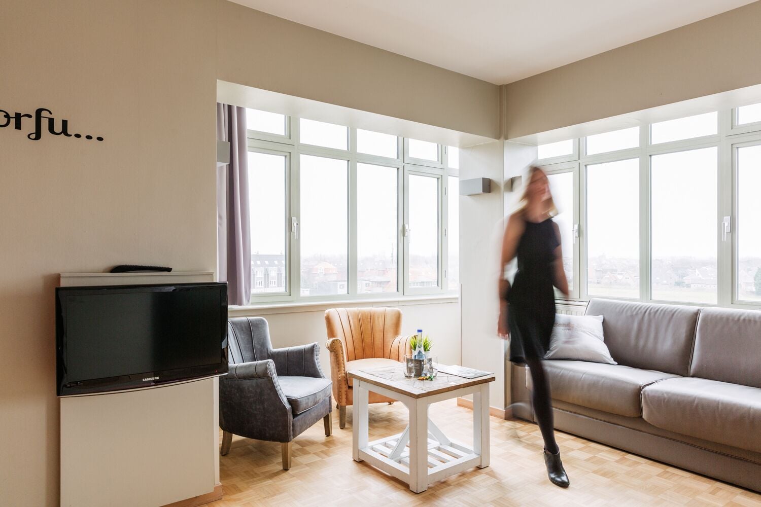 Een moderne woonkamer met een televisie, een bank, een stoel en een salontafel.