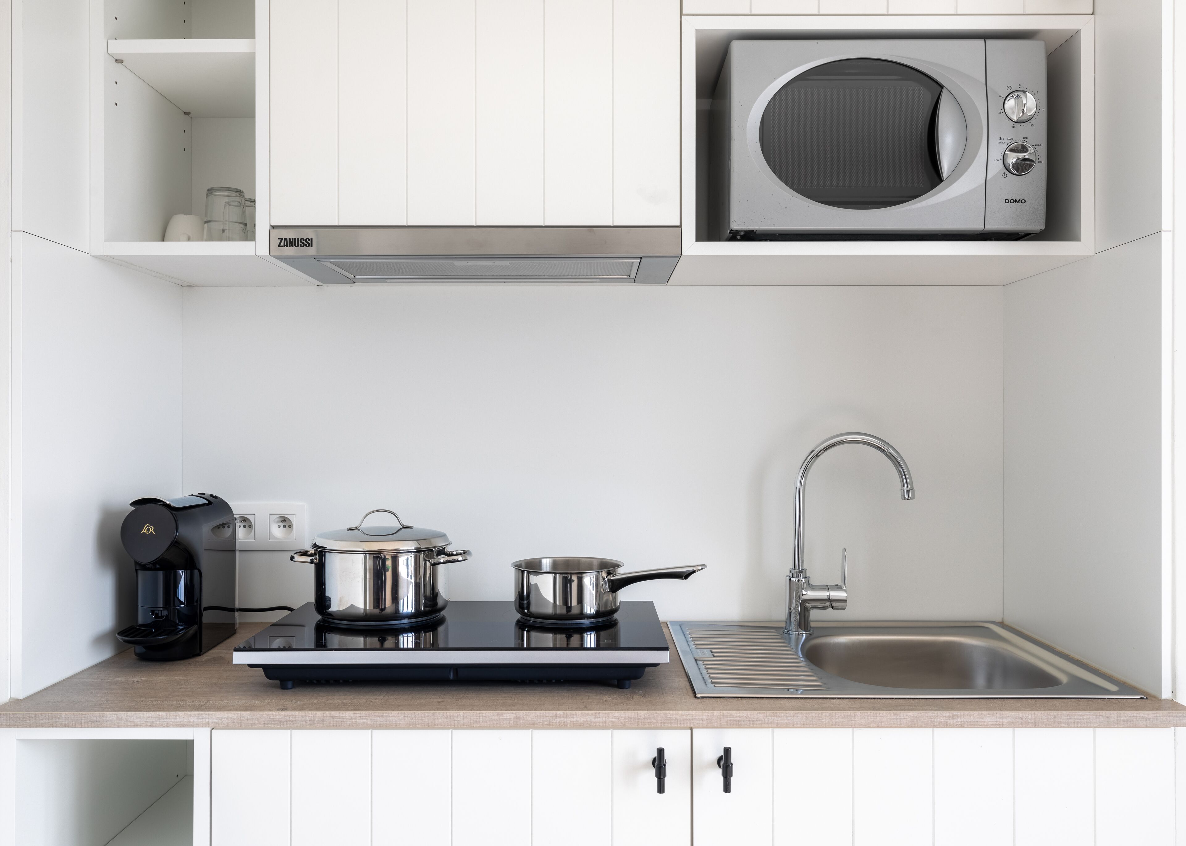 A modern kitchen with a built-in microwave, a coffee maker, a stove, and a sink.