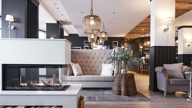 A modern living room with a fireplace, a sofa, a coffee table, and a dining area with wooden furniture. - West Bay (Middelkerke)