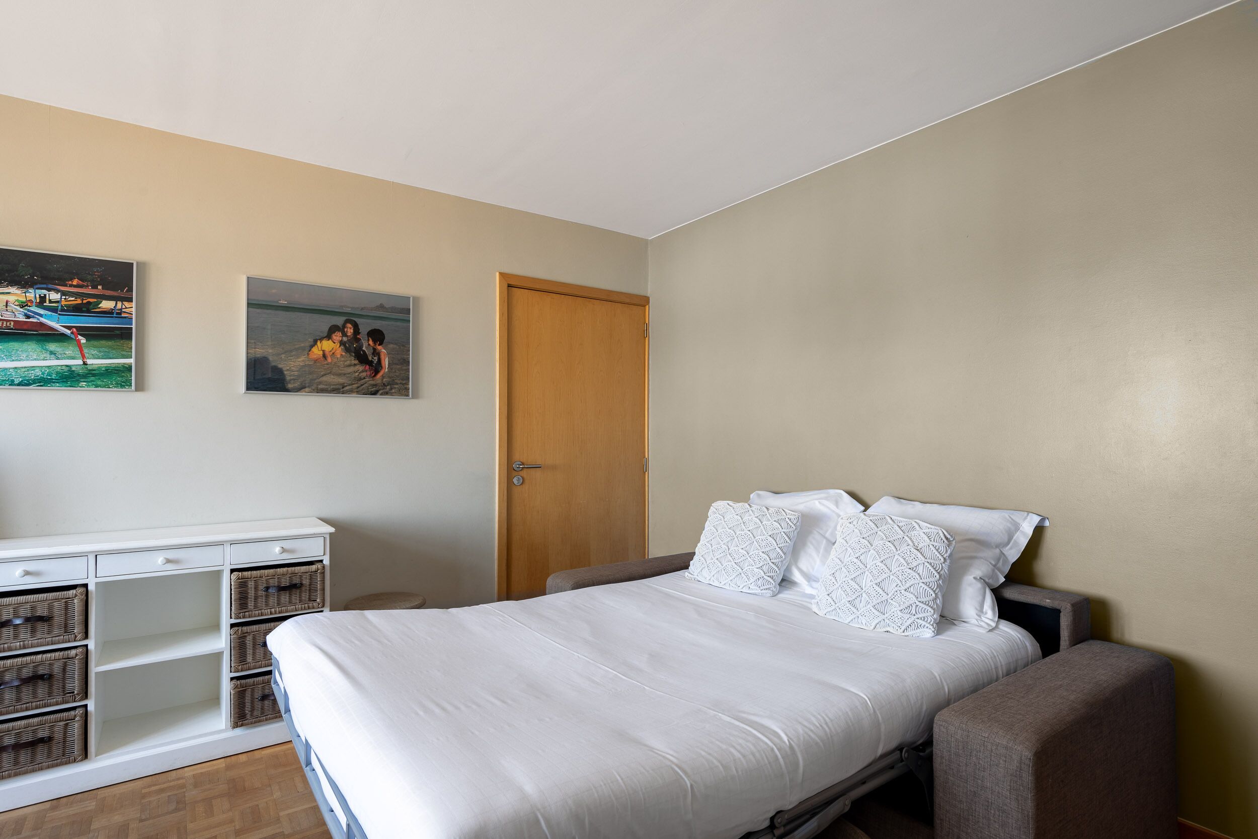 Ein Schlafzimmer mit einem Bett, einem Kleiderschrank und zwei Bildern an der Wand.